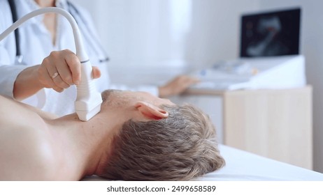 Doctor woman performing neck ultrasound exam on male patient. Medicine service concept. Thyroid gland health - Powered by Shutterstock