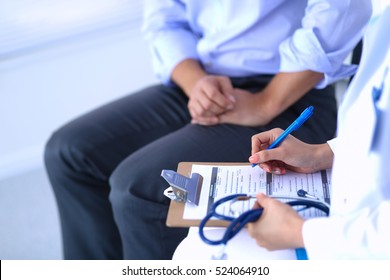 Ärztin sitzt mit männlicher Patientin am Schreibtisch