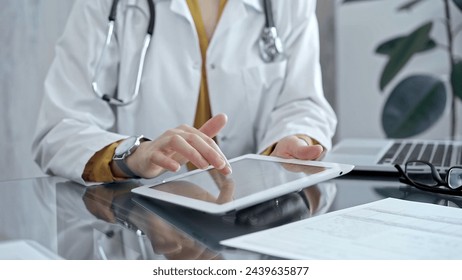 Doctor woman using tablet on the glass desk in medical office. Medicine and health care - Powered by Shutterstock