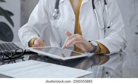 Doctor woman using tablet on the glass desk in medical office. Medicine and health care - Powered by Shutterstock