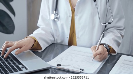 Doctor woman is working on laptop with medical reports. Healthcare professional reviews patient files and inputs data in a clinic setting. Medicine - Powered by Shutterstock