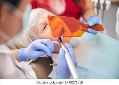 Doctor working with bonding composite filling material with ultraviolet light dental tool in modern clinic - Shutterstock ID 1798271338