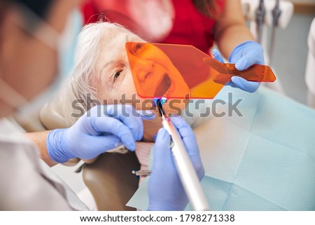 Doctor working with bonding composite filling material with ultraviolet light dental tool in modern clinic