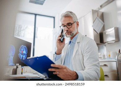 Doctor working on computer in doctor's office, looking at MRI scan, phone calling test results to patient. Doctor consulting scan with other doctors. - Powered by Shutterstock