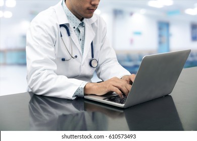 Doctor Working On Desk With Laptop Computer On Hospital Background.