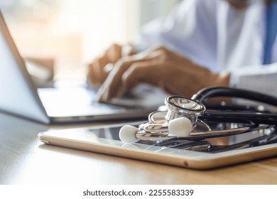 Doctor working on laptop computer with medical stethoscope and digital tablet on the desk at office in clinic or hospital. - Powered by Shutterstock