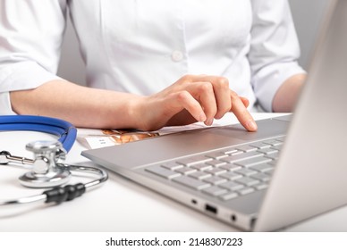 Doctor Working On Laptop. Online Patients Consultation, Using Computer For Work During Physical Examination. Woman With Stethoscope In Lab Coat Sitting At Table. High Quality Photo