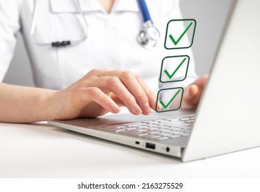 Doctor Working On Laptop And Taking Survey, Ticking Answers At Screen. Woman In Lab Coat Sitting At Table With Computer. Health Care, Medicine Concept. High Quality Photo