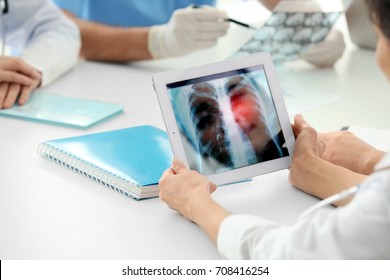 Doctor working with tablet at table in hospital. X-ray image of chest on screen. Lung cancer concept
