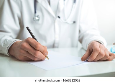 The Doctor Works At The Desk Writing Down A Medical Diagnosis.