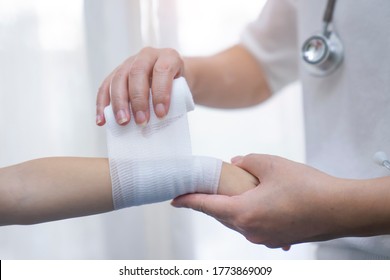 Doctor Wrapping Ace Bandage On Child's Wrist. 