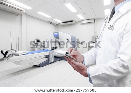 doctor writing clipboard at computed tomography or computed axial tomography scan machine in hospital room