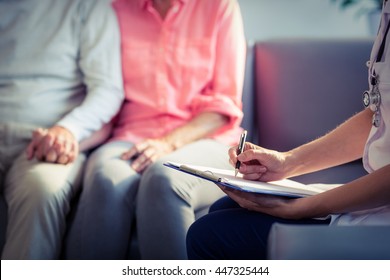 Doctor writing medical report of senior couple at home - Shutterstock ID 447325444