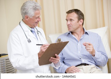 Doctor Writing On Clipboard While Giving Man Checkup In Exam Room