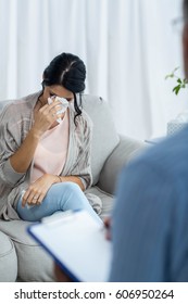 Doctor writing on clipboard while consulting pregnant woman at home