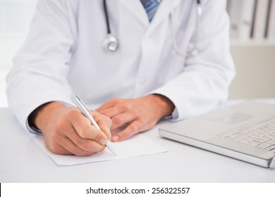 Doctor Writing On A Notepad In Medical Office