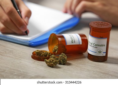 Doctor Writing On Prescription Blank And Bottle With Medical Cannabis On Table Close Up