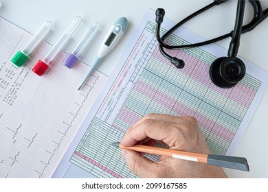 A Doctor Writing On A Vital Sign Chart.