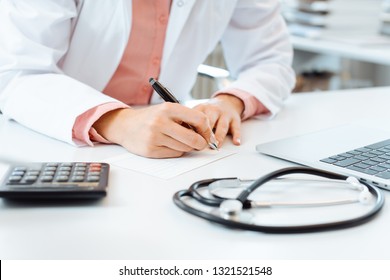 Ärztin schreibt auf ihrem Schreibtisch ein Rezept 