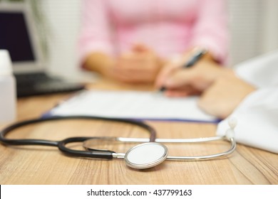 doctor is writing prescription to patient, focus on stethoscope