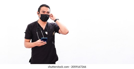 Doctor Young Latino Male Doctor Putting On Wireless Headphones, Holding His Cell Phone In His Hand For A Video Call, White Background