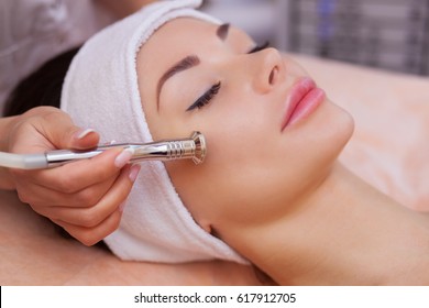 The doctor-cosmetologist makes the procedure Microdermabrasion of the facial skin of a beautiful, young woman in a beauty salon.Cosmetology and professional skin care.
