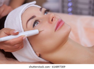 The doctor-cosmetologist makes the procedure treatment of Couperose of the facial skin of a beautiful, young woman in a beauty salon.Cosmetology and professional skin care.