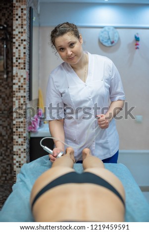 The doctor-cosmetologist performs a vacuum-roll massage of the buttocks and legs of a young woman. Masseuse does her job with the help of the apparatus of correction