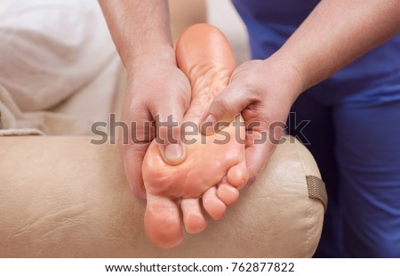 The doctor-podiatrist does an examination and massage of the patient's foot in the clinic.