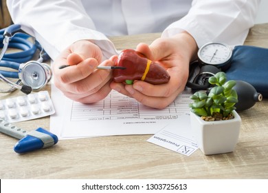 At doctors appointment physician shows to patient shape of liver with focus on hand with organ. Scene explaining patient causes and localization of diseases of liver, hepatobiliary system, gallbladder - Shutterstock ID 1303725613