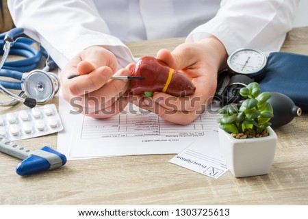 At doctors appointment physician shows to patient shape of liver with focus on hand with organ. Scene explaining patient causes and localization of diseases of liver, hepatobiliary system, gallbladder
