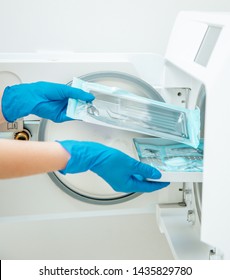 Doctor's Assistant In Blue Gloves Sterilize  Dental Steel Set Tools In Autoclave. Hospital Hygiene 