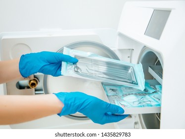 Doctor's Assistant In Blue Gloves Sterilize  Dental Steel Set Tools In Autoclave. Hospital Hygiene 