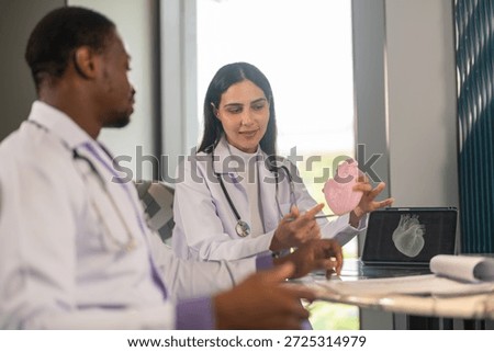 Doctors discussing cardiology case using heart model and digital scan, cardiovascular health, medical training and heart anatomy explanation, modern medical training team education, heart disease