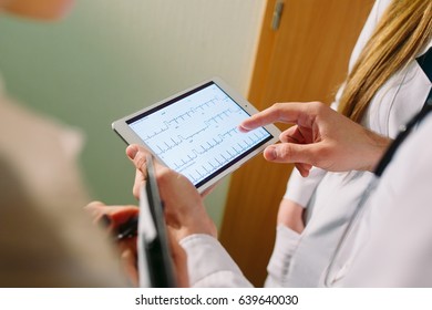 Doctors discussing patient's cardiogram on the tablet.
