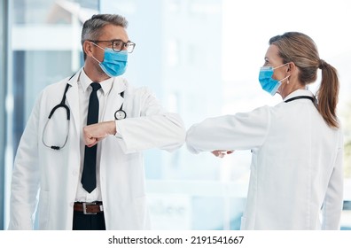 Doctors Doing Covid Safe Greeting With Elbow, Wearing Face Mask To Protect From Virus And Working In A Hospital. Heathcare Workers Talking At A Clinic, Prevent Spread Of Disease And Showing Support