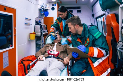 Doctors emergency or paramedics are working with a senior man patient while he lies on a stretcher in an ambulance.