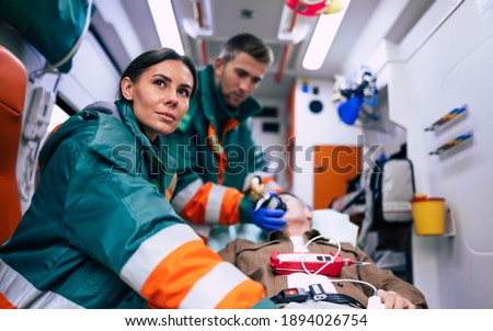 Doctors emergency or paramedics are working with a senior man patient while he lies on a stretcher in an ambulance.