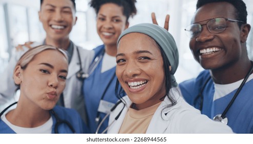 Doctors, friends and selfie in hospital for team building, solidarity or diversity for social media post. Doctor, group and teamwork with black man, women and peace for comic smile, happy and support - Powered by Shutterstock