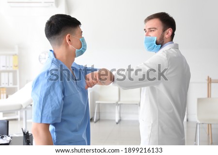 Doctors greeting each other in clinic. Concept of social distance