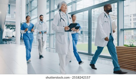 Doctors, group and walking in corridor at hospital with tablet, documents and diversity for healthcare. People, team and medical staff with solidarity, wellness and services with synergy at clinic - Powered by Shutterstock