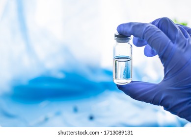Doctor`s hand in glove hold glass medicine bottle with syringe injection on blue texture surgical sterile covering background. Coronavirus vaccine development of virus antidote.Copy space.Flat lay. - Shutterstock ID 1713089131