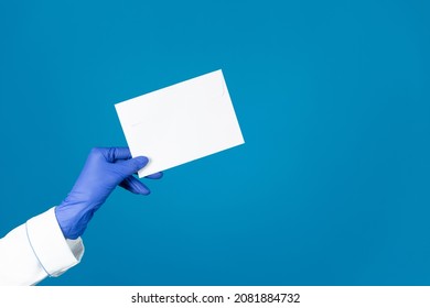 Doctors hand in a glove holds an envelope on a blue background with copy space.