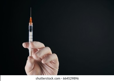 The doctor's hand  hold syringe with preparation jet from the needle. Medical man holding injector with drugs in arm isolated on white background with copy space. Botox injection syringe therapy.
