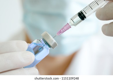 doctor's hand holds a syringe and a blue vaccine bottle at the hospital. Health and medical concepts - Shutterstock ID 1151109248
