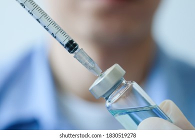 doctor's hand holds a syringe and a blue vaccine bottle at the hospital. Health and medical concepts. - Shutterstock ID 1830519278