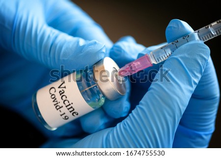 Doctor's hand holds a syringe and a blue vaccine covid19 bottle at the hospital. Health and medical concepts