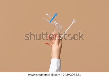 Doctor's hand with pap test tools on beige background