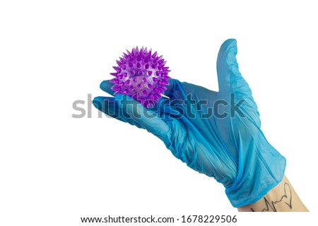 Doctor's hand in sterile gloves holding a mockup of virus of COVID-19 novel coronavirus as dangerous flu strain cases as a pandemic. World epidemia concept