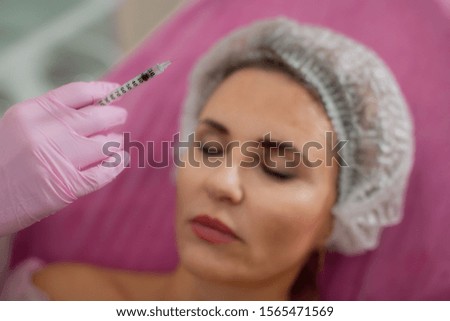 Doctor's hand with a syringe on the background of the patient with her eyes closed
